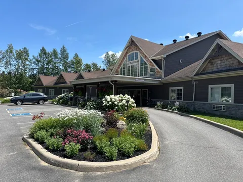 Residence building, flower beds and paved circular entrance drive.