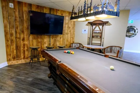 Billiards room with pool table and wall-mounted television.