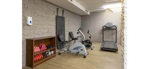 Exercise room with bikes, a treadmill and a shelf of small weights