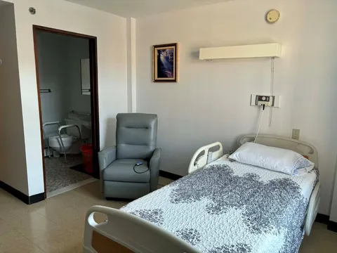 Bedroom with a single bed, armchair and framed landscape