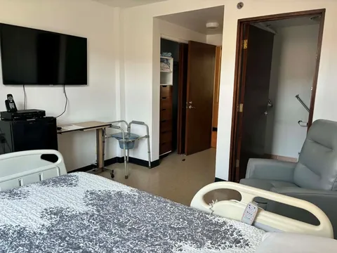 Bedroom with an adjustable bed, armchair and wall-mounted television