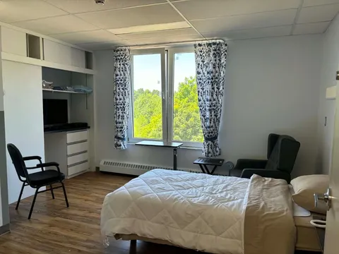 Bedroom with a single bed and armchair beside a window