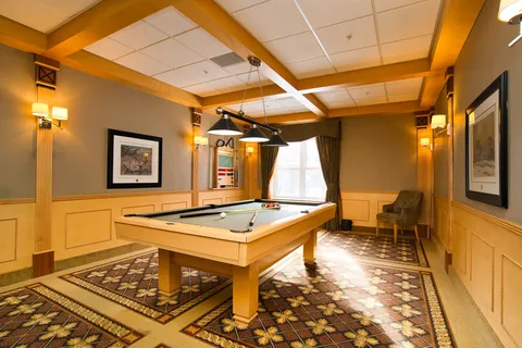 Room with a pool table, framed bird prints and a window