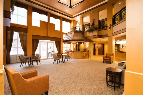High-ceilinged room with armchairs, tables and a bar