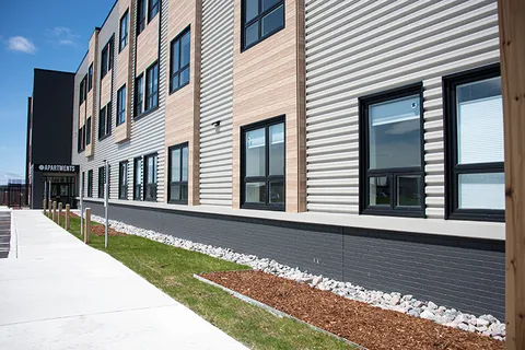 Side facade with large windows beside a paved walkway.