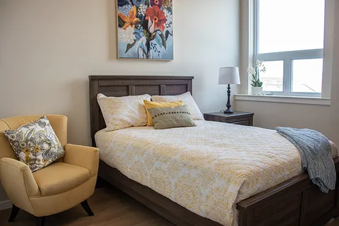 Suite bedroom with a double bed and yellow armchair.