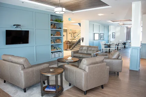 Lounge with armchairs, sofas and a wall-mounted television.