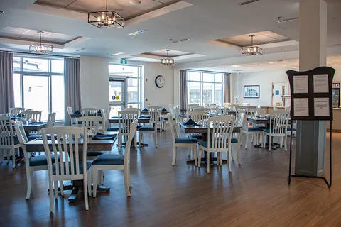 Dining room with set tables and pale wooden chairs.