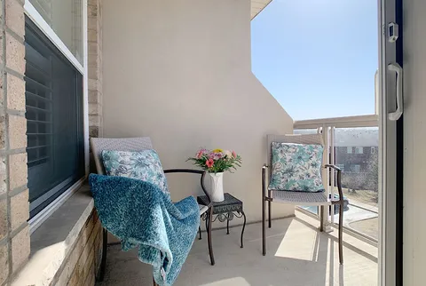 Private balcony with two chairs, a small table and flowers.