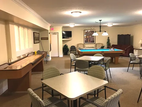 Games room with a pool table, card tables and upholstered chairs.