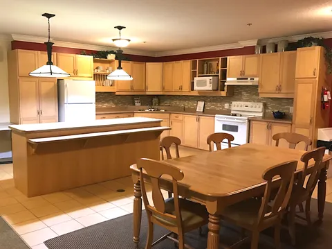Resident kitchen with wooden cupboards, an island and dining tables.