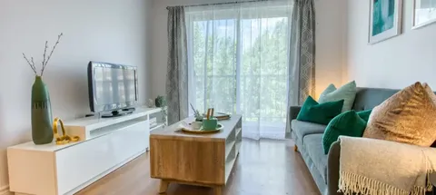 Sitting area with a sofa, television and coffee table beside a patio door