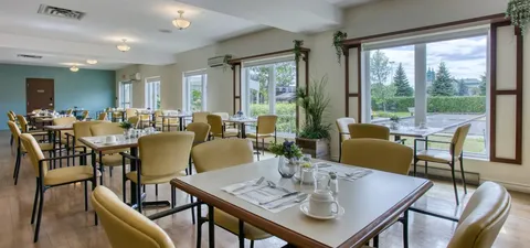 Dining room with set tables, upholstered chairs and broad windows