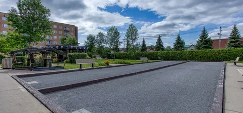 Gravel courts beside benches, covered swings, trees and hedges