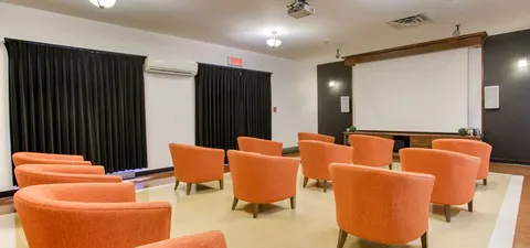 Room with orange armchairs facing a blank projection screen