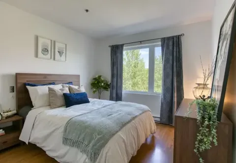 Bedroom with a blue and white bed, curtains and a bedside lamp