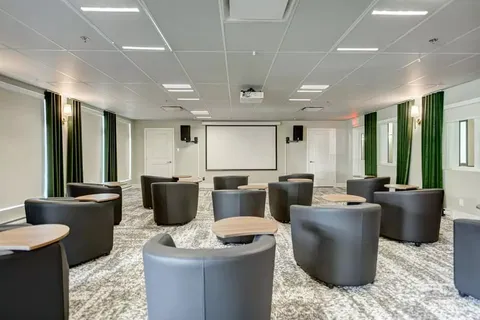 Theatre with armchairs and tables facing a blank projection screen