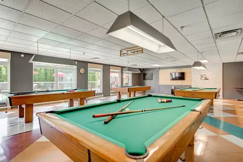 Room with several pool tables and a television