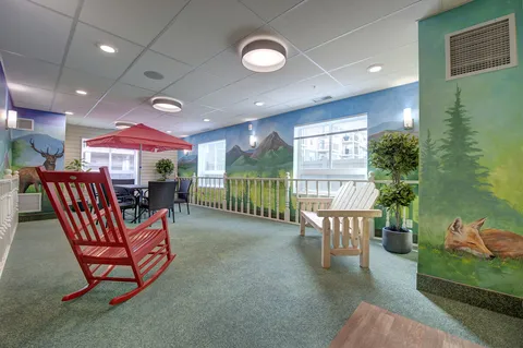 Room with rocking chairs, railings and a landscape wall mural