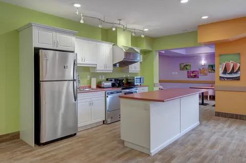 Kitchen area with white cupboards, a refrigerator and an island