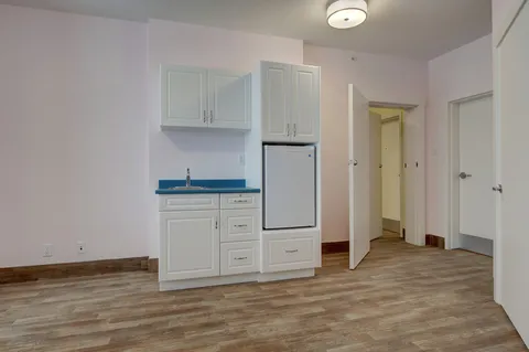 Empty room with a kitchenette, refrigerator and open doorway
