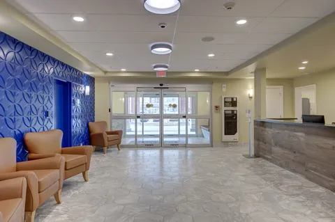Entrance lobby with armchairs, a reception desk and glass doors