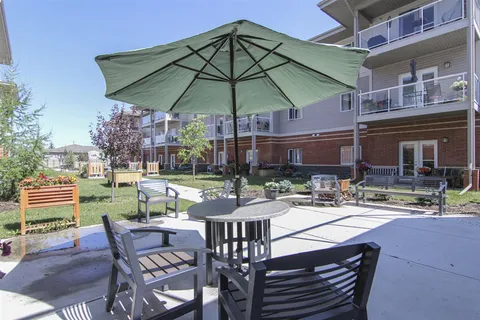 Patio with tables, chairs and a green umbrella beside an apartment building