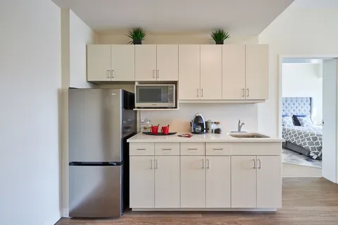 Kitchenette with white cabinets, a refrigerator, a microwave and a sink
