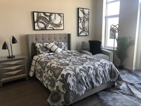 Bedroom with a patterned bedspread, an armchair and abstract wall art