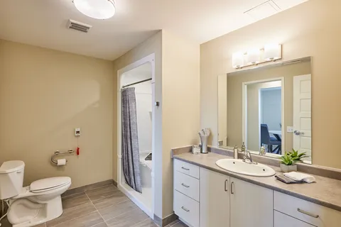 Bathroom with a toilet, a sink, a large mirror and a shower curtain