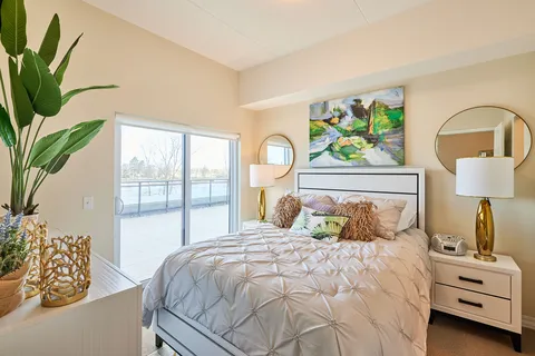 Bedroom with a white bed, gold lamps, round mirrors and doors to a balcony