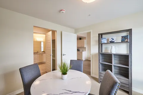 Room with a round table, upholstered chairs and open shelving