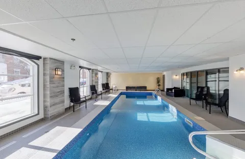 Indoor swimming pool with handrails, windows and chairs
