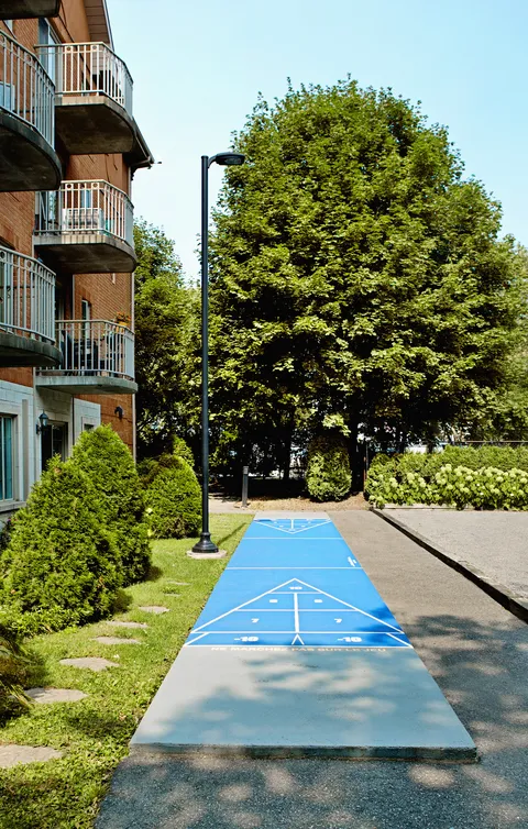 Outdoor shuffleboard court beside planted beds and residence balconies