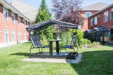 Lawn and covered swing seating in a courtyard between two red-brick buildings