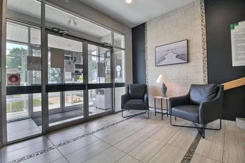 Glass entrance doors beside two dark armchairs and a framed photograph of a wooden pier