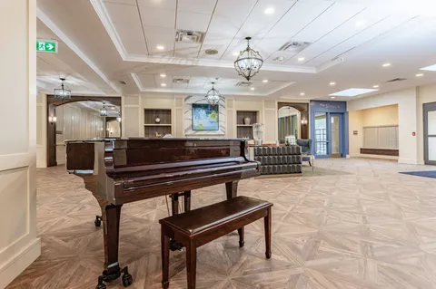 Atrium lounge with a grand piano, seating and large windows.