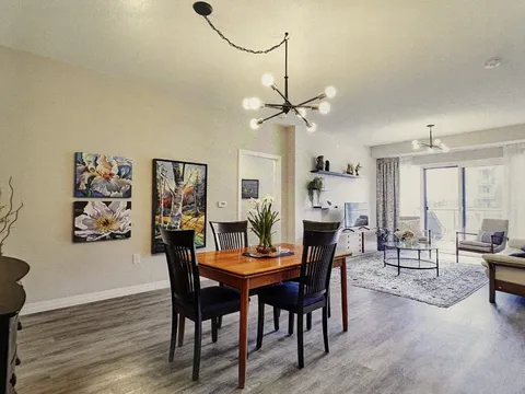 Suite dining and living area with a table, chairs and balcony door.