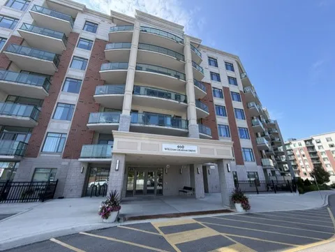 Residence entrance below balconies beside a paved driveway.