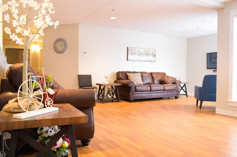 Room with brown sofas, a blue armchair, wooden flooring and a landscape picture