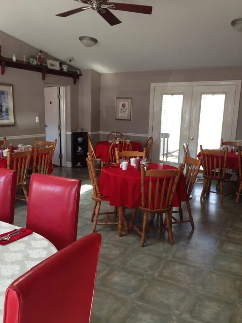 Dining area with red tablecloths beside a glass door.