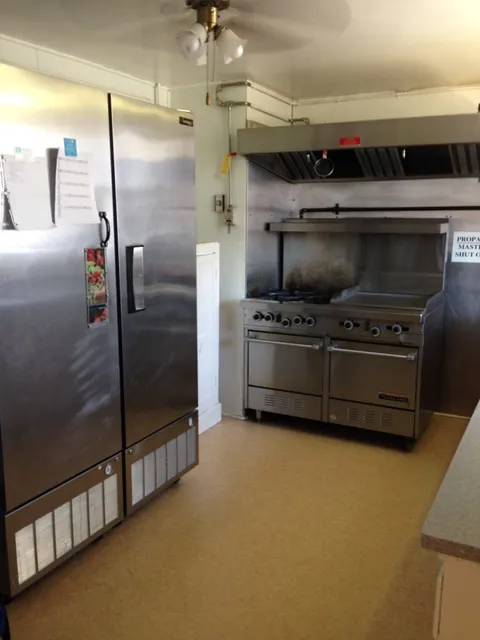 Kitchen with a stainless steel refrigerator, cooker and work surfaces.