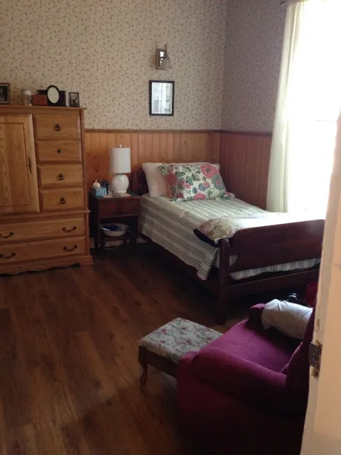 Bedroom with a single bed, dresser and armchair.