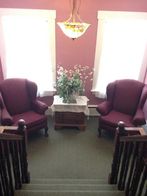 Sitting area with armchairs beside bright windows.