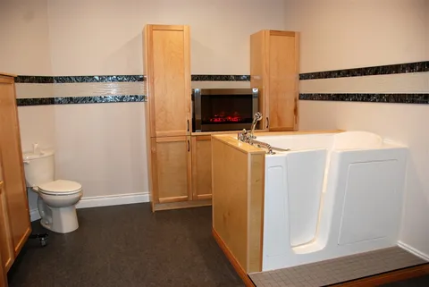 Accessible bathroom with a walk-in tub, toilet and tall cabinets.