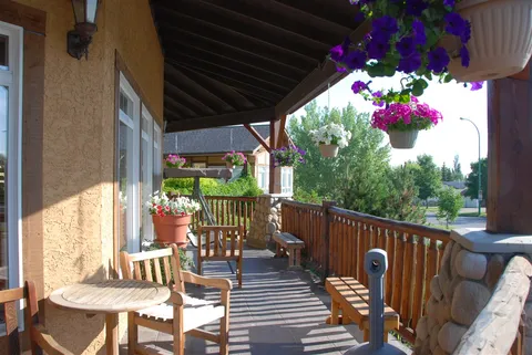 Covered patio with a small table, chairs and hanging flower baskets.