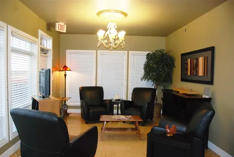 Sitting room with leather armchairs, tables and a fireplace.