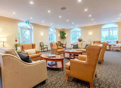 Sofas and tan armchairs around tables beside arched windows