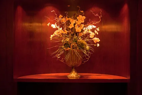 Flower arrangement in an urn displayed in a wood-panelled alcove