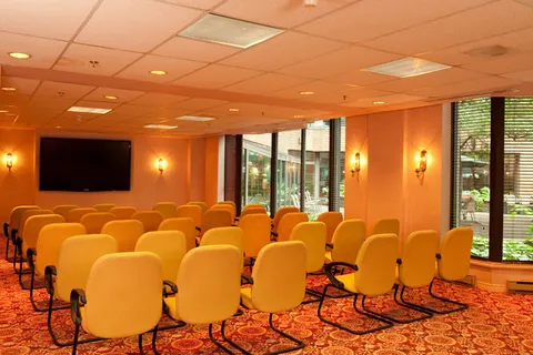 Room with rows of yellow chairs facing a blank screen